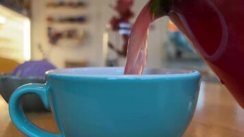 Gießen Himbeere Tee von Glas Teekanne in Blau Tasse von Strom von heiß trinken im Herbst warm oben Behandlung zum Erkältungen Cranberry Tee Erdbeere köstlich gut zum Gesundheit richtig Ernährung Behandlung video