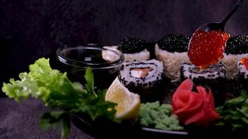 Sushi with red and black caviar Close-up of uramaki sushi rolls with red caviar, salmon, cucumber and avocado isolated on a black background. Delicious traditional Japanese food with sushi rolls. video