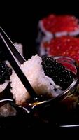 Sushi com vermelho e Preto caviar fechar-se do uramaki Sushi rolos com vermelho caviar, salmão, pepino e abacate isolado em uma Preto fundo. delicioso tradicional japonês Comida com Sushi rolos. video