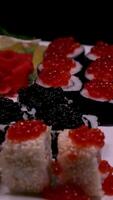 Sushi with red and black caviar Close-up of uramaki sushi rolls with red caviar, salmon, cucumber and avocado isolated on a black background. Delicious traditional Japanese food with sushi rolls. video