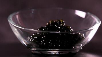 negro caviar en un blanco plato , aceitunas y limón en un negro antecedentes video