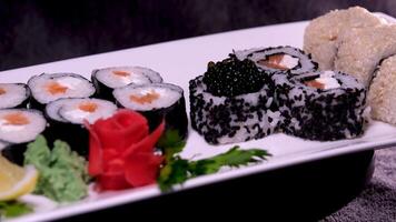 sushi med röd och svart kaviar närbild av uramaki sushi rullar med röd kaviar, lax, gurka och avokado isolerat på en svart bakgrund. utsökt traditionell japansk mat med sushi rullar. video