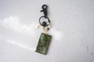 Key chain or bag charm on greyish white background. Top view. photo