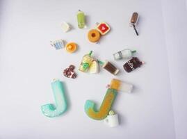 miniature food and alphabet made of clay and resin with colorful toys on white background photo