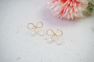 Close up of earrings on white background with pink carnation flower photo