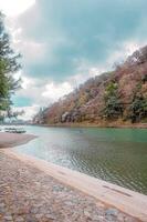 beautiful landscape of a river with a boat on it and a mountain in the background. photo