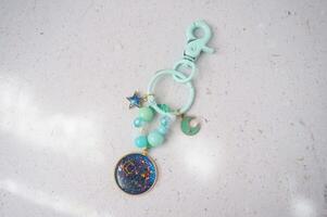 Key chain or bag charm on greyish white background. Top view. photo