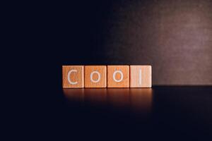 Wooden blocks form the text Cool against a black background. photo