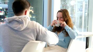 jongen en meisje tieners in cafe zitten door venster pratend hebben pret hebben pret eerste datum verhouding school- cafetaria restaurant ontspannende drinken koffie uitgeven een dag in stad leven van echt mensen video