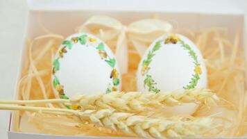 im Box auf Tabelle gemalt Eier gemalt Eier Stickerei mit Bänder auf Eierschalen drei Ährchen von Weizen erscheinen Ostern Kunst Handarbeit handgemacht Technologie zum Herstellung Eier Landwirtschaft Gans Strauß Eier video