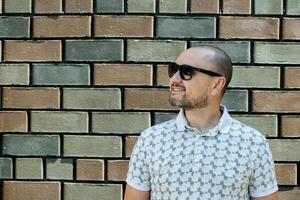 sonriente hombre con Gafas de sol en contra pared foto