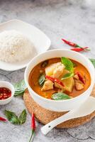 Traditional Thai chicken red curry with fresh vegetable and herb in bowl on table, Thai food concept with rice photo