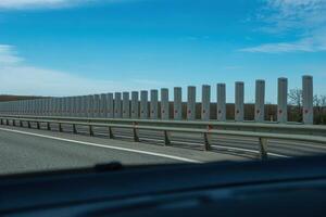 A road with a long line of metal posts with red hearts on them. The road is empty and the sky is clear. photo