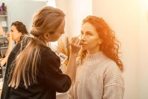 Make-up artist makes a professional make-up of a young woman in the studio. photo