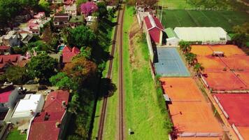 Empty railroad track, railway view in green grass among town houses, city outskirts, suburban buildings. photo