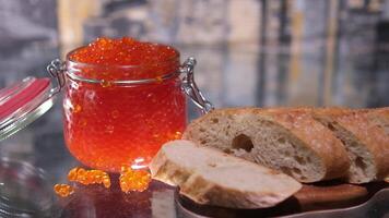 avec une couteau à propager beurre sur pain dans le Contexte une verre pot avec caviar finement tranché baguette avec Saumon caviar et beurre, délicieux sandwich avec pain, beurre et Naturel rouge caviar video