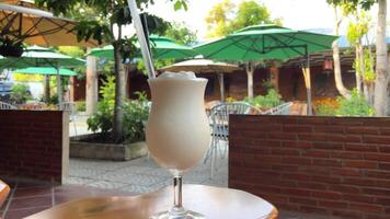 Vanilla cocktail with whipped cream in a tall glass on wooden table. Background with copy space. Summer milkshake in glass video