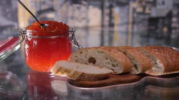 con un' coltello per diffusione burro su pane nel il sfondo un' bicchiere vaso con caviale sottilmente affettato baguette con salmone caviale e Burro, delizioso Sandwich con pane, burro e naturale rosso caviale video