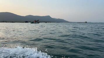 shooting from a motor boat against backdrop of fishing boats, village and mountains video