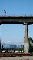 pattulo brug over- fraser rivier- trein voorbijgaan onder brug. detailopname schot van technologisch plaats verspreide ijzer balken voor de bouw van nieuw brug tegen de backdrop van bergen en lucht video