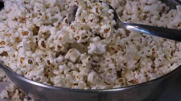 stirring popcorn with a spoon close-up in an iron bowl preparing popcorn for an evening movie viewing video