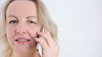 beautiful adult woman close-up face in hands phone talking on the phone answer yes no that she waves her head plays with her eyes bright emotions questions on a white background empty space for text video