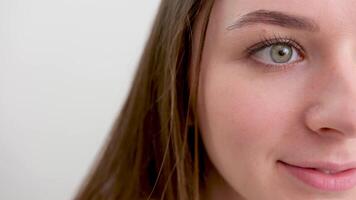 close-up half face place for text ad beauty grooming cream young smiling woman looking happy on white background. Big smile on her face, looking beautiful and cute with hands touching her cheek. video