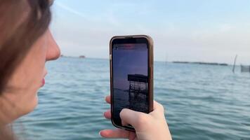 ragazza prende un' immagine di un' Casa su il acqua su un' mobile Telefono video
