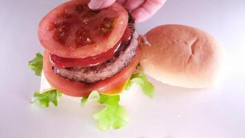 falten ein Burger erstellen ein Burger Startseite mit ein Brötchen stellen Zwiebel Schnitzel Tomate gießen Senf Ketchup stellen Käse und Grüner Salat Verbreitung Mayonnaise auf das Brötchen das ganze Prozess im anders s video