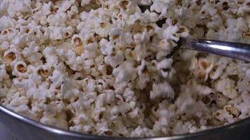 cooking popcorn at home in a special machine caramel filling caramelized popcorn recipe close-up delicious treat for movie stir and pour caramel icing popcorn grains iron utensil appetizing snack video