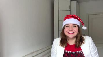 menina com vermelho cabelo e santa chapéu detém uma Natal neve brinquedo bola dentro dela mão. malabarismos e arremessos. ela sorrisos com dele boca Largo abrir. venda período. Alto qualidade fhd com lento movimento video