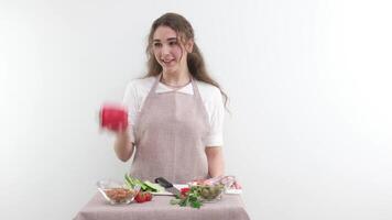 lento movimento jovem menina mulher jogando vermelho Sino Pimenta rindo cozinhando mostrar apetite delicioso vegetal salada vegetariano Comida cozinha avental e toalha de mesa 1 cor legumes saudável video