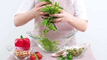 donna con mani spargimento le foglie in giro bicchiere piatto goffamente cucinando insalata freschezza dieta diverso verdure su tavolo imparare per cucinare a casa irriconoscibile persone video