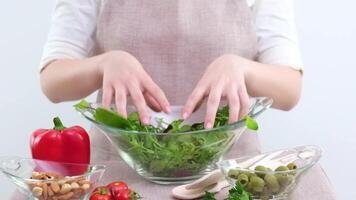 Close-up female hands stirring with wooden spoon ingredients vegetables in fresh delicious salad, unrecognizable family mother and daughter vegetarians prepare meal dish with red pepper green leaves video