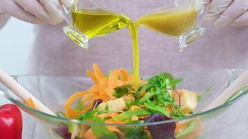 salad in glass bowl from two jugs stream oil sauce with mustard and honey ingredients front tablecloth olives tomatoes red peppers carrots Bright colors are not recognizable people fresh vegetables video