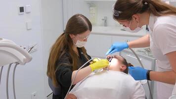 dentaire plus récent Bureau Nouveau équipement prothèses canaux plombages moderne dentaire équipement moyen coup de femelle dentiste dans noir manteau, masque et gants en utilisant dentaire microscope à examiner les patients les dents video