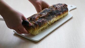 apple strudel sprinkled with poppy seeds with large knife female hands close-up cut dessert red apple space for text background ad cooking show recipes cooking homemade restaurant pastries yeast dough video