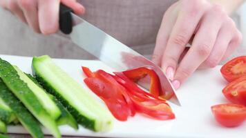 detailopname met een groot mes vrouw handen besnoeiing rood klok peper De volgende naar de ingrediëntengezond op te slaan supermarkt bazaar scherp mes blad mooi teder manicure jong handen beige schort keuken schort video