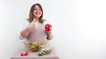 schön Frau zwinkert zeigen rot Glocke Pfeffer im Hand mit andere Hand zeigen Daumen oben gesund Essen zum Gewicht Verlust Öffnung Mund und lächelnd stark Raum zum Text Kochen Show Kommen Sie beitreten uns Diät video