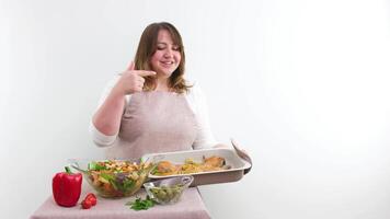 sexy woman cook shows thumb up holding baking sheet with chicken points to baking sheet with finger and licks food cooking tasty eat space for text cooking show recipes homemade food housewife video