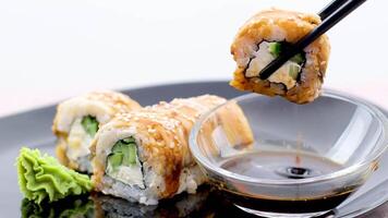 Close-up girl dips the rolls into the soy sauce on a black background. Chopsticks to dip the rolls in soy sauce, close-up. video