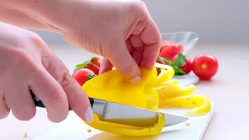 un cocinero es rebanar un amarillo pimienta en un corte tablero.el cocinero es cuidadosamente corte eso dentro Delgado rebanadas para un ceviche receta. video