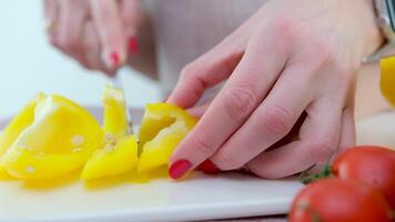 adulto insegna bambino per tagliare verdure madre aiuta figlio per tagliare giallo campana Pepe avvicinamento mani coltello e porcellana lavagna salutare verdure primo passaggi nel cucinando formazione video