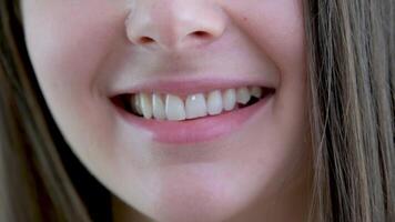 sonrisa de un encantador niña con Perfecto blanco dientes cerca arriba. Perfecto blanco dientes y un sonrisa atentamente incluso blanco dientes frecuencia natural labios espacio para texto natural belleza naturalidad marrón pelo video