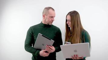 Ukraine Winniza 01.01.2024 Mann und Frau im Hände mit Apfel iPad MacBook und iPhone Ausrüstung ein Paar von Geschäft Menschen im das Büro auf ein Weiß Hintergrund aussehen beim das Bildschirm lösen Probleme video