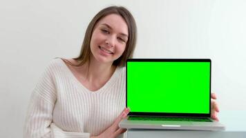 Over the shoulder shot of a business woman working in office interior on pc on desk, looking at green screen. Office person using laptop computer with laptop green screen, sitting at wooden table video