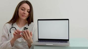 a nurse with a phone in her hands is typing a text message in the foreground a laptop with a white chroma key screen empty space for text video