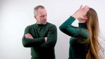 A man and a woman on a white background posing in a studio photo shoot press their backs to each other straighten their hair strike a pose, confident look, green clothes a couple of people video