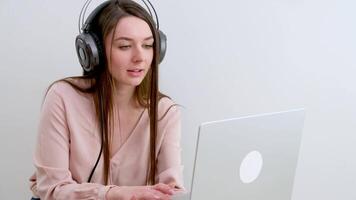 Attractive and happy young female student studying online, sitting at desk, using laptop computer, having chat, waving, education concept. video