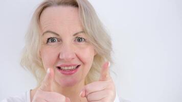 I choose you beautiful middle-aged woman with two hands with index fingers points at us to camera smile close eyes on white background blonde face bite lower lip smile joy space for advertising text video